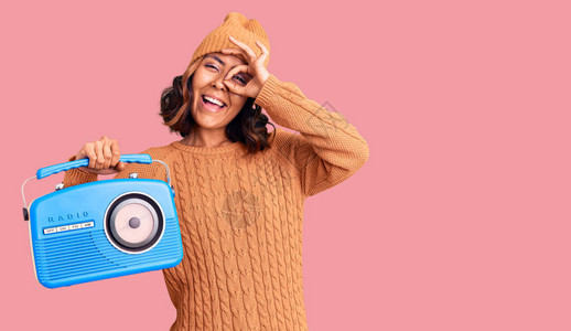 年轻漂亮的混血女子拿着老式收音机微笑着开心地做着好手势图片