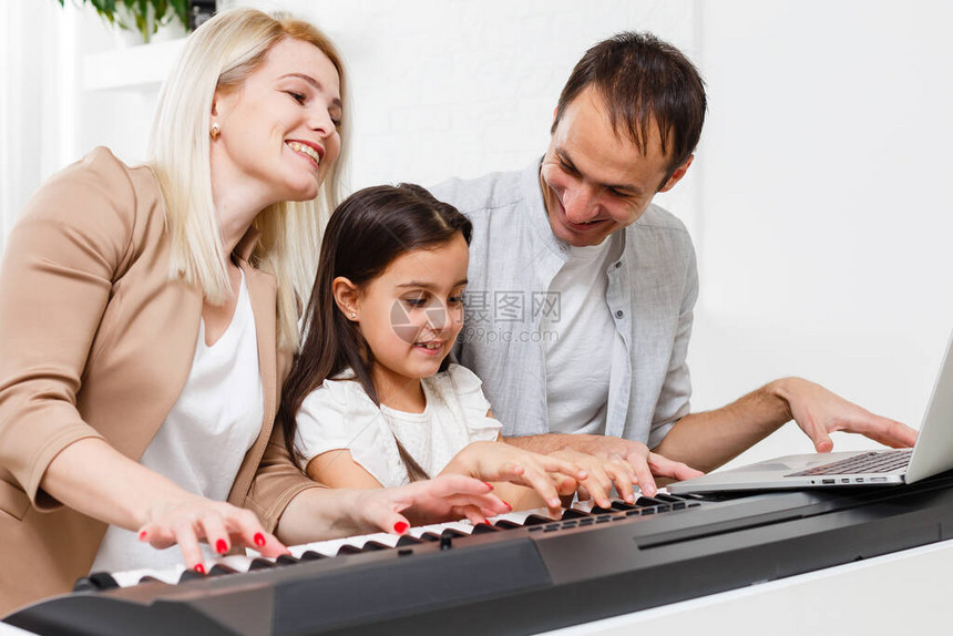 幸福的家庭母亲父亲和女儿在家弹钢琴图片
