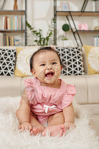 穿着淡粉红裙子坐在家毛地毯上可爱的快乐背景图片
