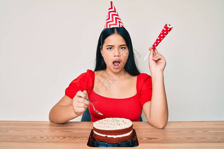 年轻的亚洲女孩在庆祝生日时用蛋糕当着惊吓的面吃蛋糕图片