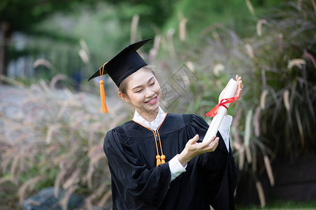 有吸引力的亚洲女学生毕业帽和长袍手拿证书庆祝开学日如此自豪的幸福图片