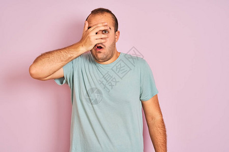 身穿蓝色散装T恤的年轻人站在孤立的粉红色背景上图片
