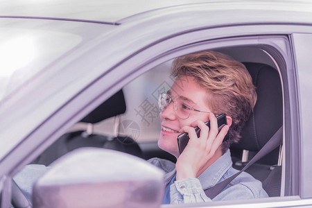 金发男孩坐在车里直视前方微笑着在电话里说话图片