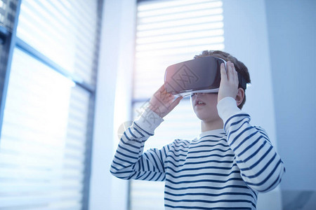 使用VR头盔复制空间的10岁高加索男孩无法识别的横向中低角度图片