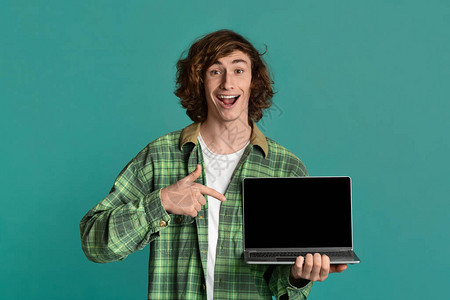 兴奋的千百年的家伙指着笔记本电脑上面是绿石背景空屏幕图片