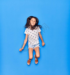 可爱的西班牙裔儿童女孩穿着休闲服微笑快乐在孤立的蓝色背景图片