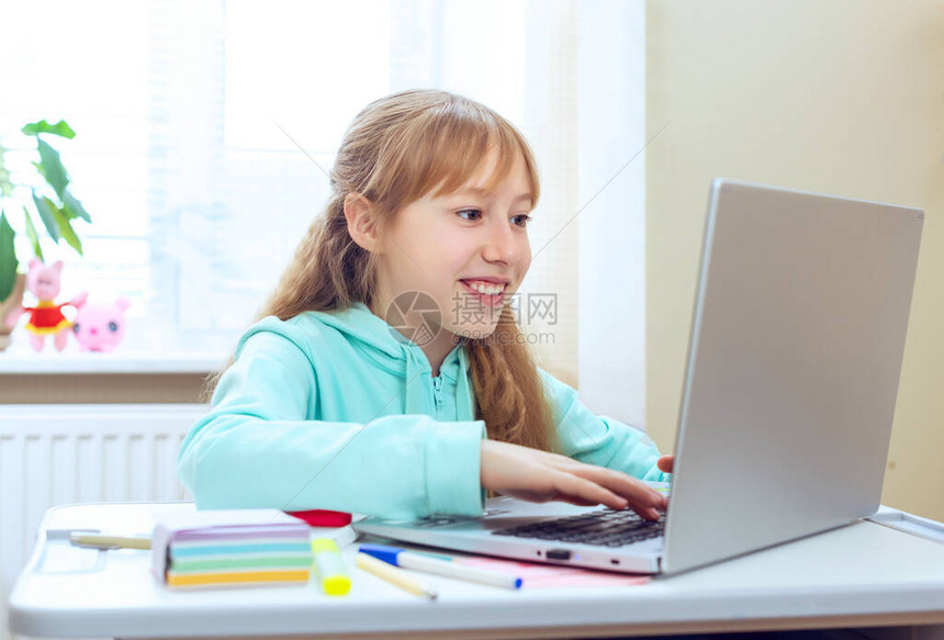 十几岁的女孩使用电脑坐在房间的办公桌旁做作业图片