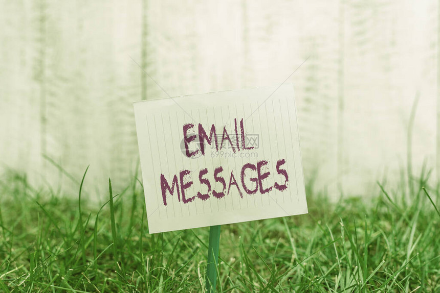 显示电子邮件消息的文本符号展示使用电子邮件发送的消息的商业照片附在棍子上并放置在绿色草地图片