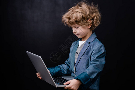 聪明的小学生在黑色背景下在网上冲浪时拿图片