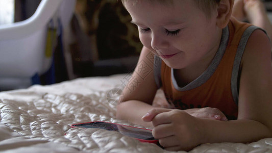 儿童在家中的床上玩智能手机图片