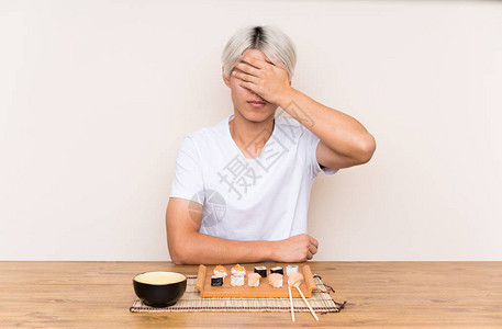 年青的亚洲男人在一张桌子上吃寿司用图片