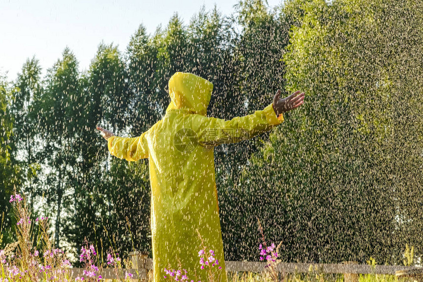 一个身穿黄色雨衣的男子站在雨中图片