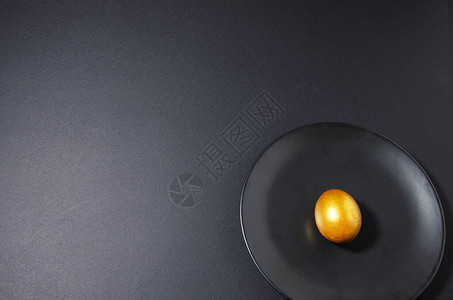 黑色盘子和黑色背景上的金蛋图片