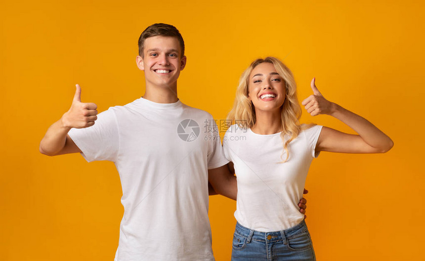 推荐快乐的一对年轻夫妇在黄色背景上展示拇图片