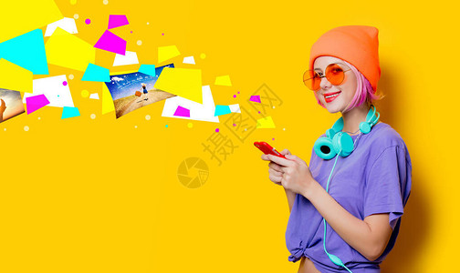 穿紫色衣服耳机和黄色背景移动电话的年轻时装女孩图片