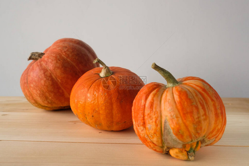 万圣节和感恩节秋天的概念3个不同大小的橙色南瓜在一张木桌上秋天的背景侧面图片