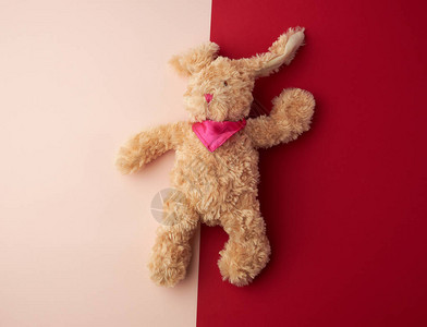 Toy棕色加白兔躺在粉红背景图片