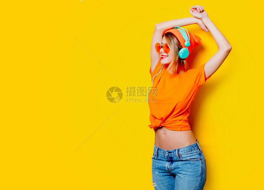 有橙色眼镜和黄色背景耳机的年轻时尚女青年图片