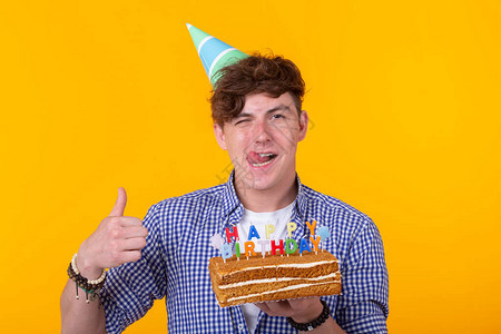 正面的年轻人拿着一个快乐的生日蛋糕和两盏燃烧的灯光图片