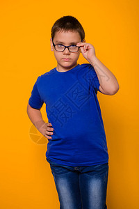 一个戴眼镜的小男孩的肖像和一件蓝色T恤衫站图片