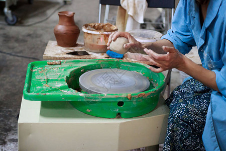 在陶器的第一堂课上的新学生试图在陶器轮子上用粘土制图片