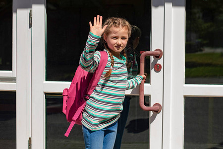 一个带着粉红色背包的女孩打开了学校的大门图片
