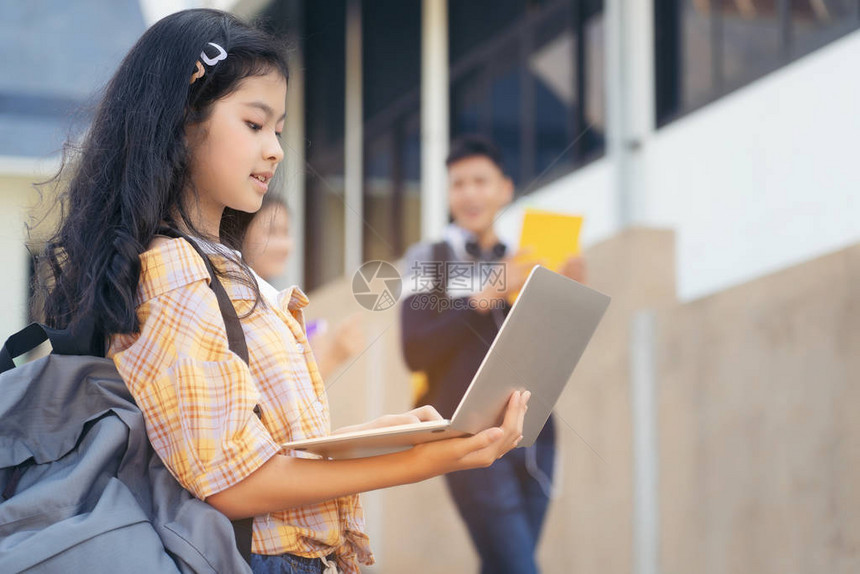 年轻学生少女高中生背着书包拿着labtop与图片