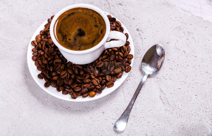 一杯咖啡加咖啡豆的碟子和混凝图片