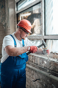 一名辛勤工作的建筑工在建筑工地施工用锤图片