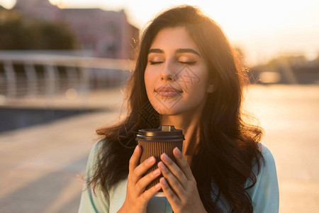 清静的女孩享受着外送咖啡在日落图片