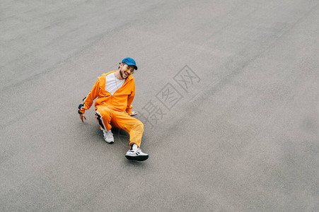 穿着时尚明亮街头服饰的快乐嘻哈舞者坐在柏油操场上的照片图片