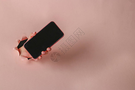 女手握着智能手机在粉红纸圆洞中穿孔关图片