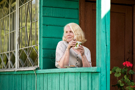 金发大龄妇女在阳台喝咖啡图片