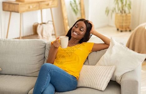 黑人女士在家坐在沙发上喝咖啡图片