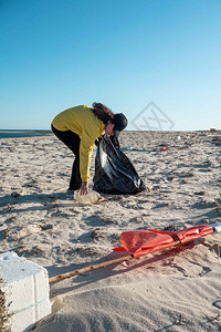 女人捡垃圾和塑料用垃圾袋清洁海滩反对气候变化和海洋污染的环保图片