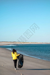 女人捡垃圾和塑料用垃圾袋清洁海滩反对气候变化和海洋污染的环保图片