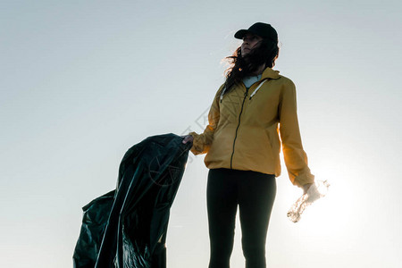 女人捡垃圾和塑料用垃圾袋清洁海滩反对气候变化和海洋污染的图片