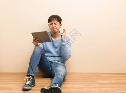 年轻的人坐着用平板电脑交叉手指图片