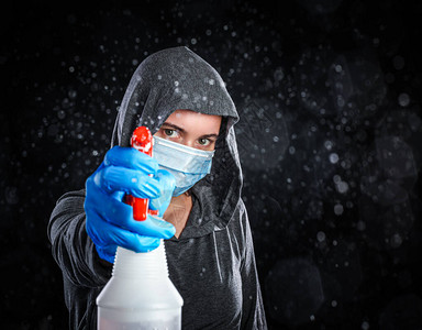 戴医疗面具和清洁手套的妇女喷洒了消毒剂的雾气图片