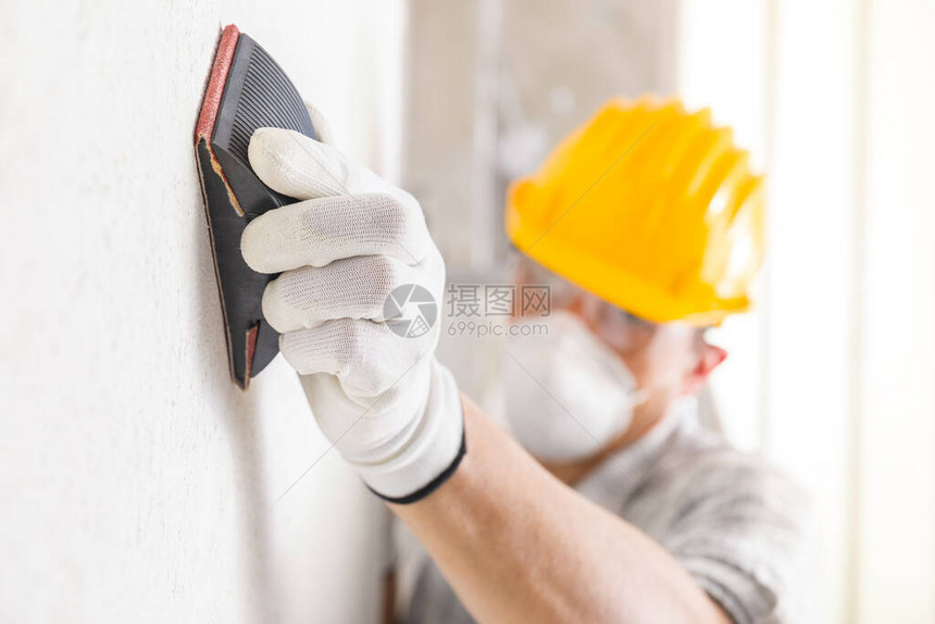 粉碎板或画家在翻修期间将白墙新石膏表面砂成沙子图片