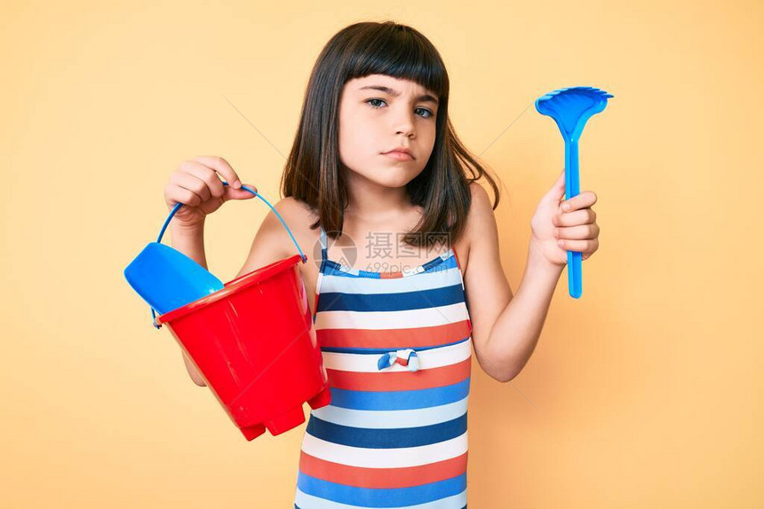 玩夏季铲子和木桶玩具的年轻小女孩毫无头绪又含糊不清的表情图片