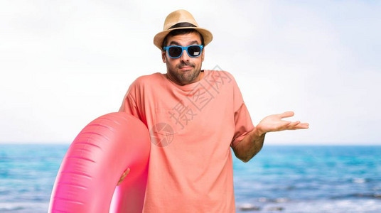 戴着帽子和太阳镜的男人在暑假做着不重要和怀疑的手势图片