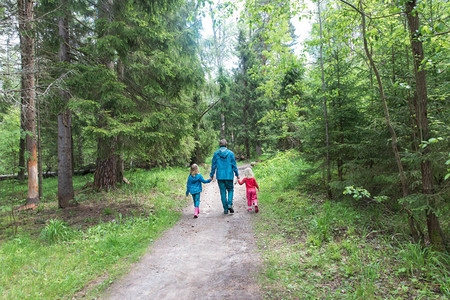 父亲和两个孩子在森林里散步图片