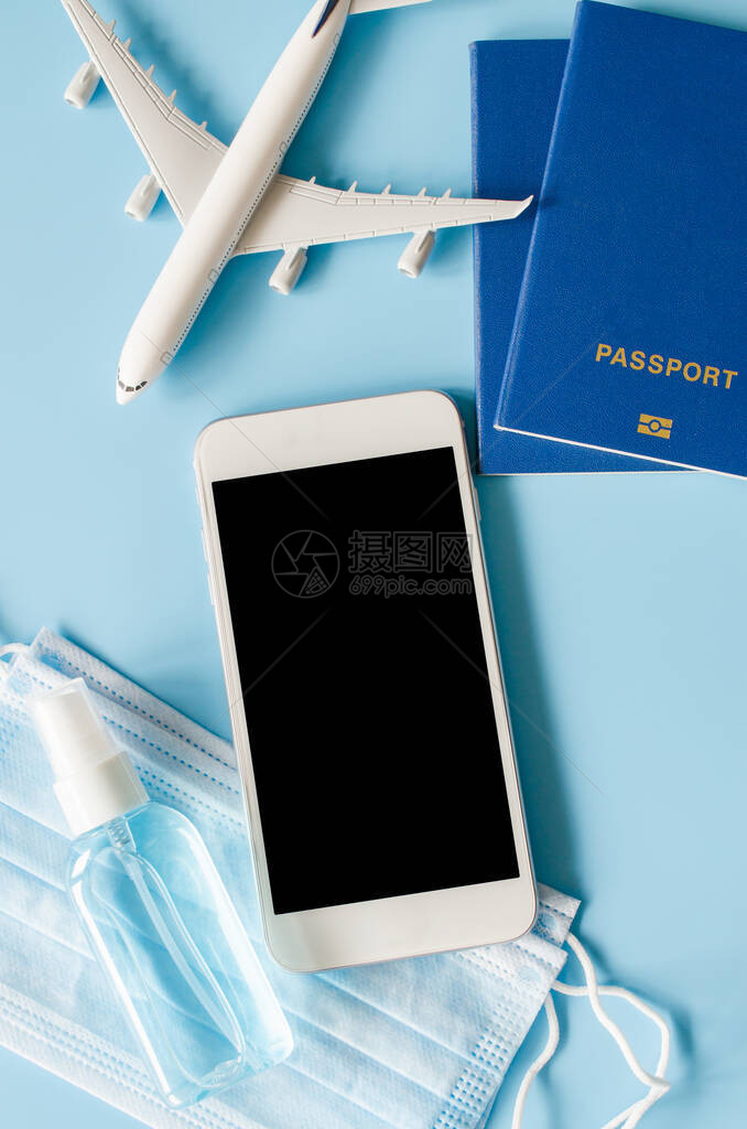 冠状和检疫后的旅行和旅游规划蓝色背景上带有飞机模型护照面罩和洗手液喷雾的智能手机模型带有复制图片