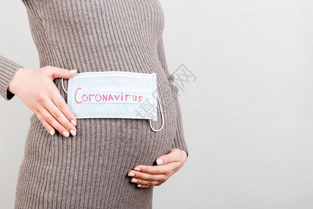 在怀孕女孩肚子上戴医疗面罩隐形保护冠状概念covid图片