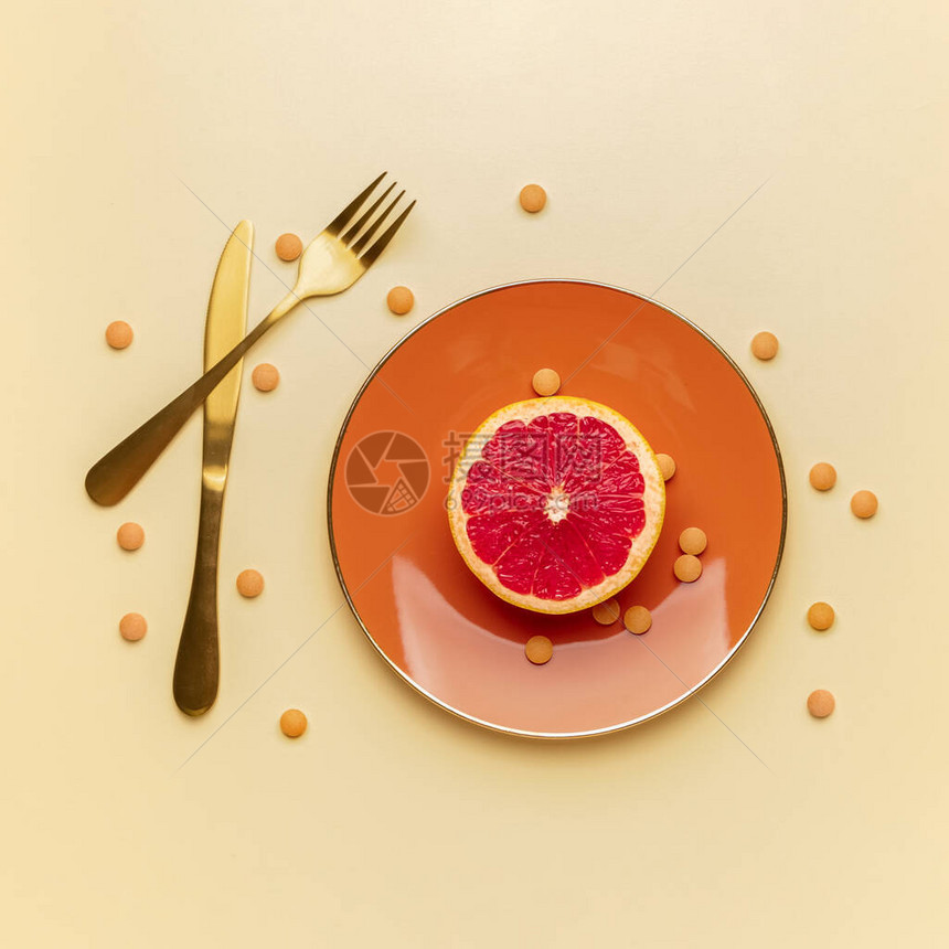 彩色背景上装有减肥药和葡萄柚的盘子图片