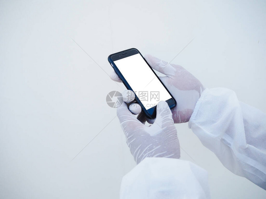 身着PPE套件制服的医生或科学家的特写手拿着一部带有空白屏的智能手机图片