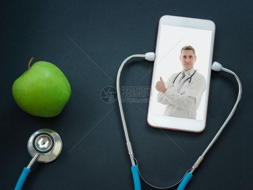 智能手机屏幕上的医生桌上的听诊器和青苹果医生在线概念在线医疗交流和虚拟界面上的图片