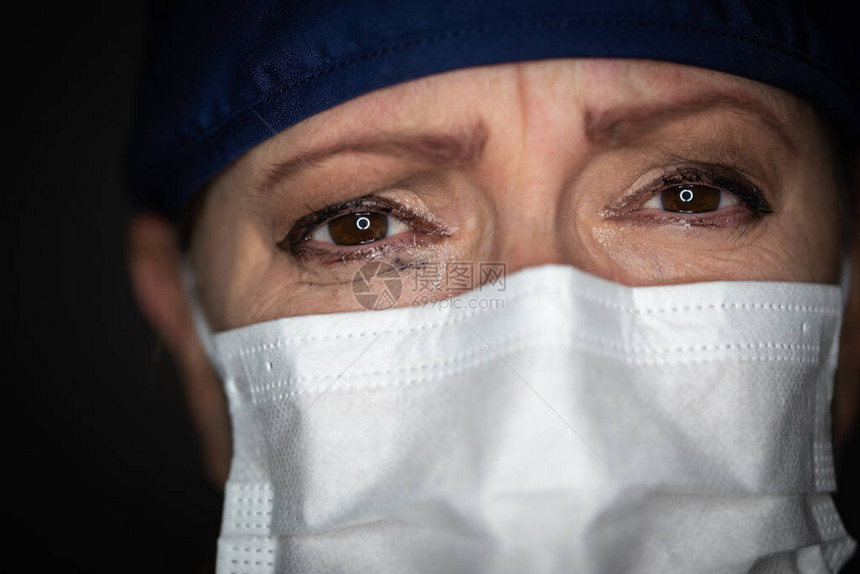 在黑暗背景上戴面罩的女医生或护士遭受了痛图片