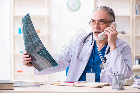 拿着X光射线图像的医生在打电话图片